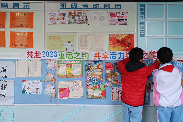 2023年2月13日上午，北京小学通州分校，两名同学在教室外布置文化墙。 视觉中国 图