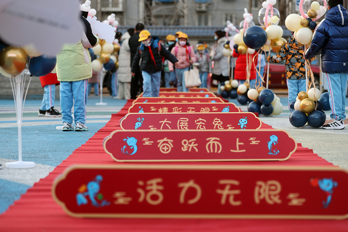2023年2月13日上午，北京小学通州分校门口秩序井然，同学们从老师手中接过棒棒糖，跨过红毯走进校园。视觉中国 图