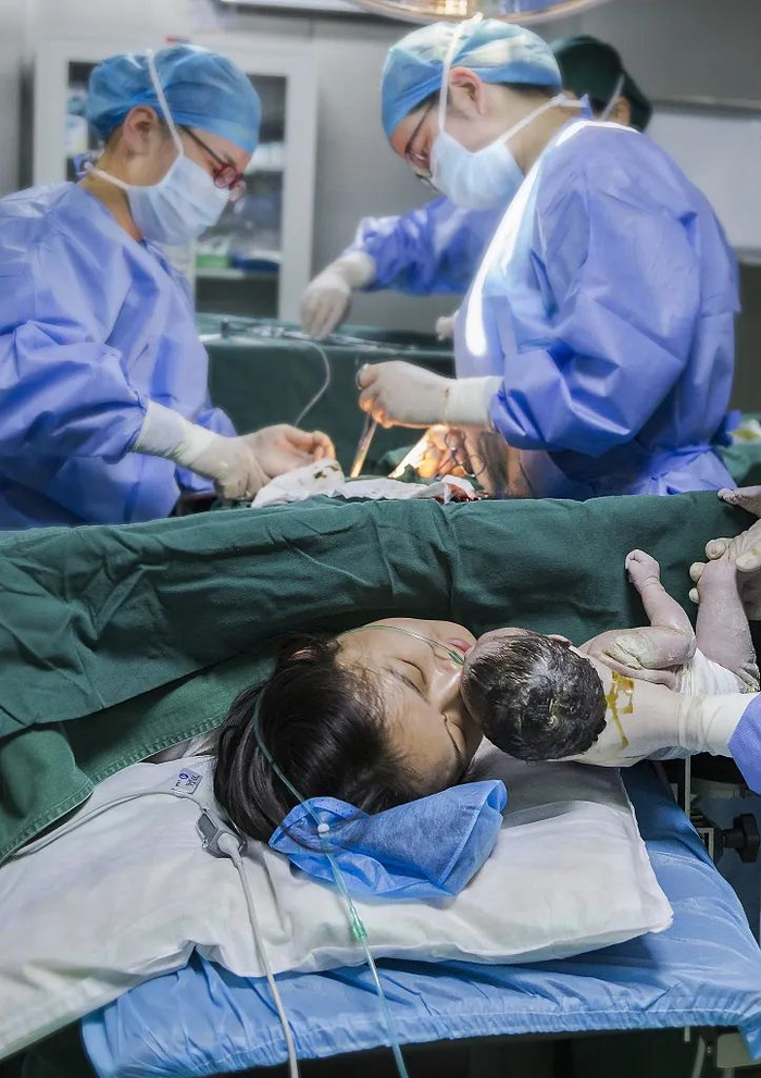 安徽宣城一名产妇在亲吻新生儿。视觉中国供图。