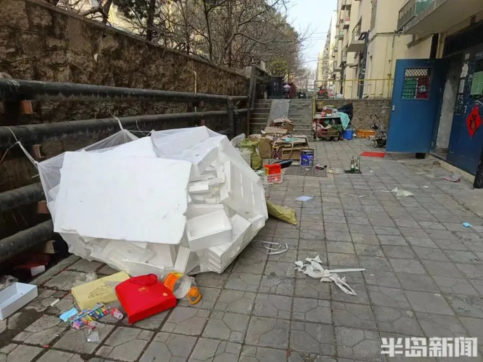 西山花苑2号楼附近，地面上堆放许多杂物和垃圾