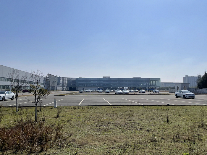 威马临街停车场，透过栏杆，能看到稀稀落落停着未上牌的新车