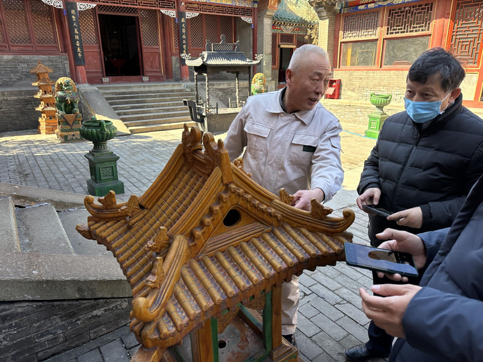在琉璃渠村，随处可见琉璃制品的样子，图为郭立生讲解村里的琉璃方地灯。新京报记者 王巍 摄