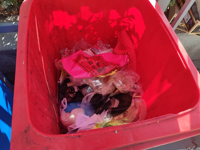 岳各庄社区前摆放的有害垃圾红桶，里面堆着各种杂物