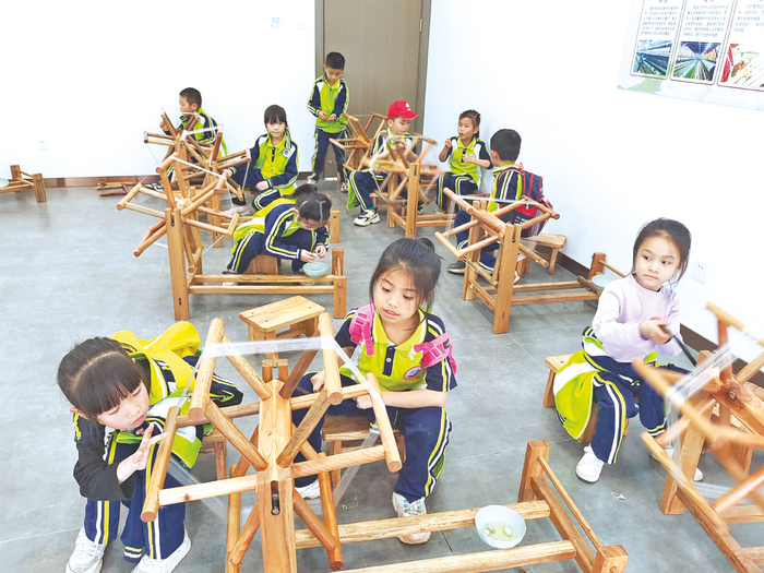     南宁市邕宁区第一小学一年级学生学习古法缫丝。    （莫永 摄）