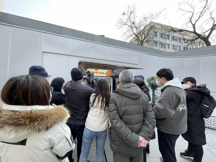 众人围观、拍摄煎饼果子机器人制作煎饼的过程 摄影/李莹