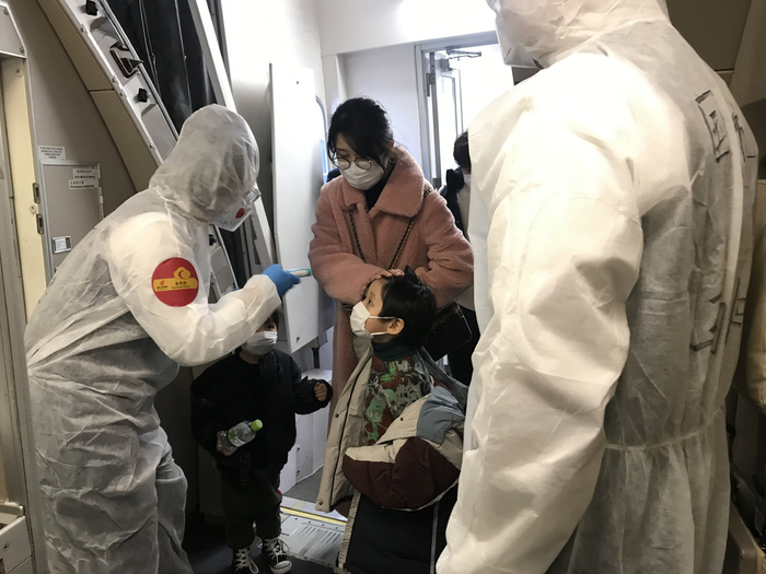 2020年2月16日，国航包机再赴日本接207名同胞回国。图为“时代楷模”国航金凤乘务组为旅客测量体温。（国航供图）