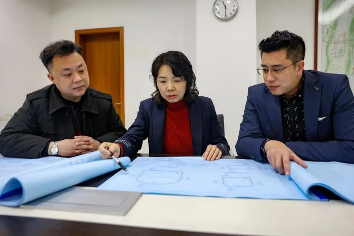 ▲林莉和团队成员看设计图纸