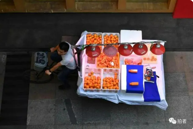 ▲2020年5月29日下午，成都市中心的成府路，水果商贩骑着三轮车去摆摊。新京报资料图