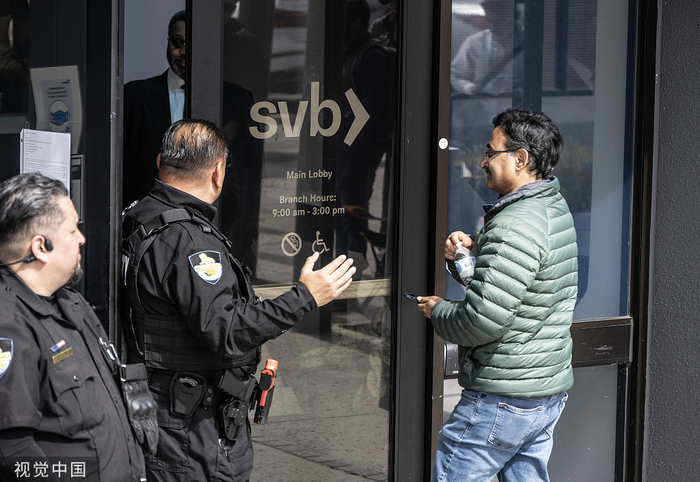当地时间2023年3月13日，美国圣塔克莱拉，硅谷银行外，当客户在排队时，保安让一名男子进入大厅。视觉中国 图