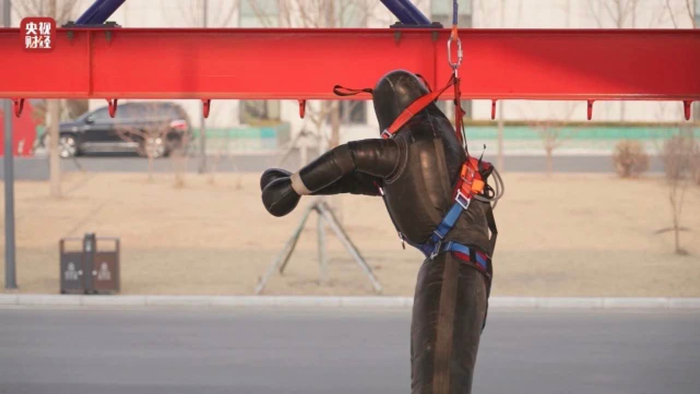 工作人员为假人穿上三点式安全带做测试。 来源：央视