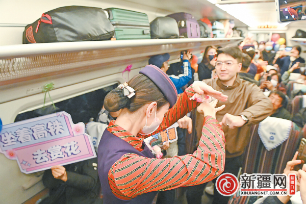 3月17日，在乌鲁木齐至吐哈站D9372次高铁赏花专列上，列车员和旅客跳舞互动。（全媒体记者陈岩摄）