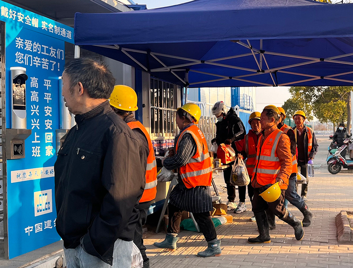  假证被收后，樊二在工地宿舍外等着被人接进去。另一边，下了工的工人们陆续刷脸进入宿舍。本文图片均由澎湃新闻记者&nbsp;巩汉语&nbsp;邹佳雯 摄