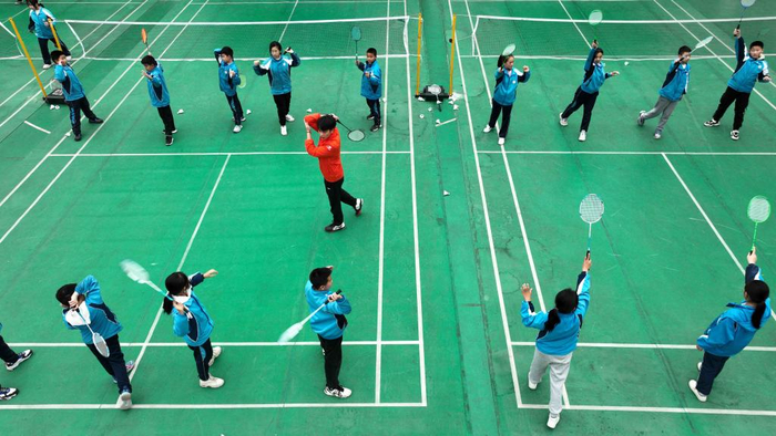 在贵州省锦屏县城关第四小学，教练员指导学生进行羽毛球训练（3月7日摄，无人机照片）。