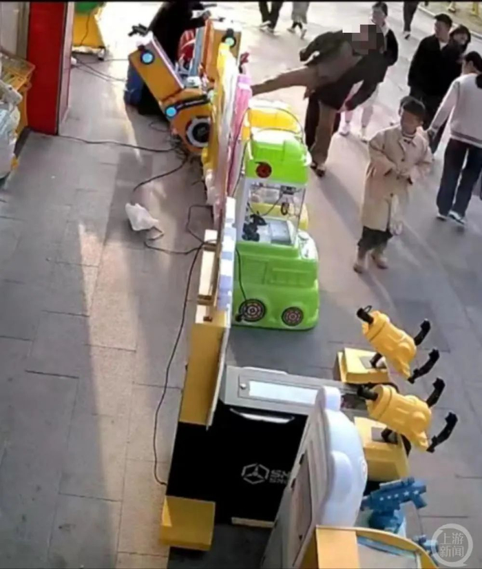 视频显示，女子连续脚踢街边玩具店的儿童游戏机。/视频截图