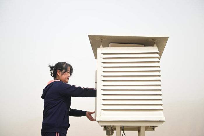 　　3月22日，在青海省黄南藏族自治州同仁市气象局，朱宇蓉在查看百叶箱。 新华社记者 张龙摄