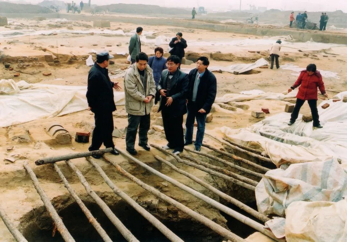 2002年，在新郑郑韩故城制陶作坊遗址，马俊才（前排左三）向来访专家介绍遗址情况。