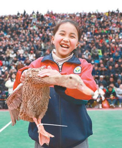 3月26日，一名小学生在贵州省首届“美丽乡村”篮球联赛总决赛赛前游戏环节中赢得奖品鸭子。新华社记者 刘 续摄