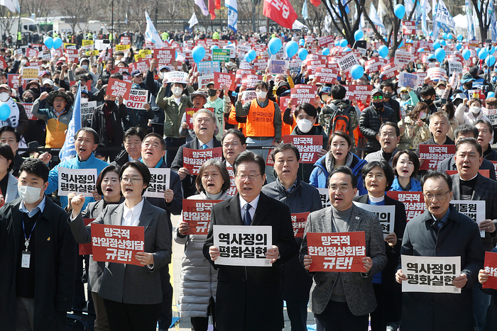 　　当地时间2023年3月18日，韩国首尔，韩国共同民主党党首李在明（中）和其他抗议者在举行的抗议集会上高呼口号，抗议3月16日韩国总统尹锡悦与日本首相岸田文雄举行的韩日首脑会谈。视觉中国 图