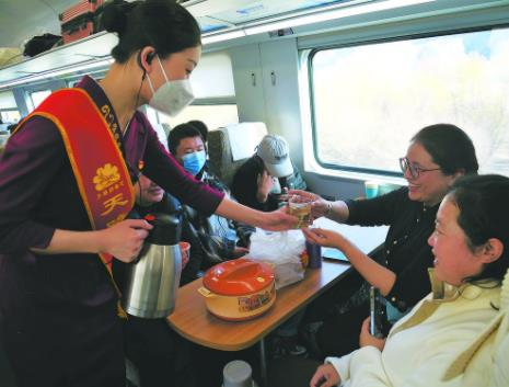 图为“天路格桑花”便民服务队员为旅客送上热茶。