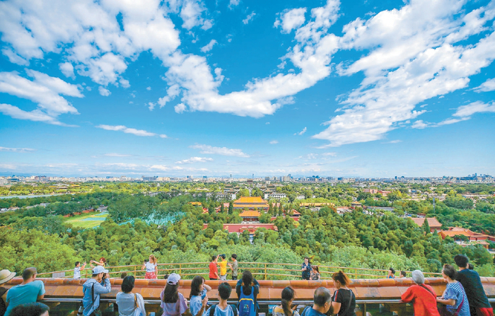 游人站在景山万春亭向北远眺，由近及远，蓝天白云下的鼓楼、北京奥林匹克塔、燕山山脉，依稀可辨。 本报记者 武亦彬摄