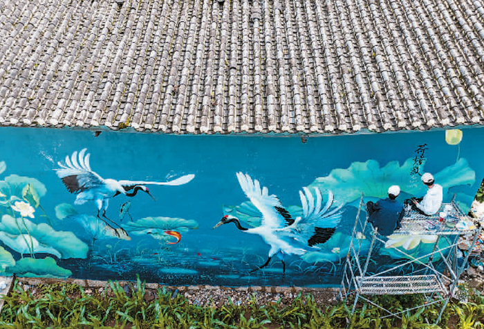 刘小备（右）在村子里创作 （无人机照片） 江文耀 摄