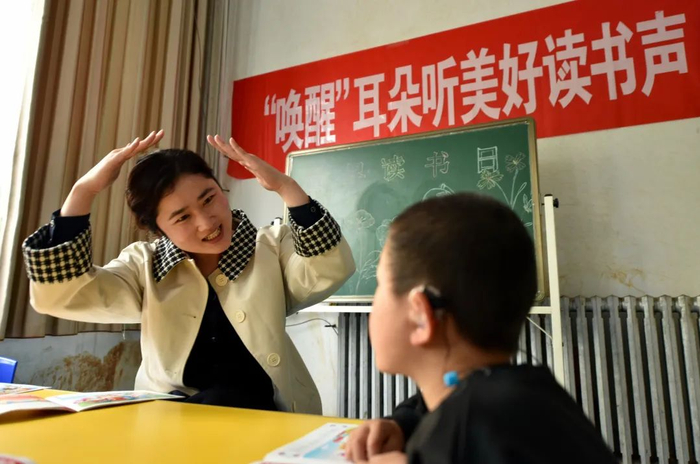 在山东省聊城市茌平区听力语言康复中心，志愿者在给听障儿童朗读绘本《西游记》。赵玉国 摄