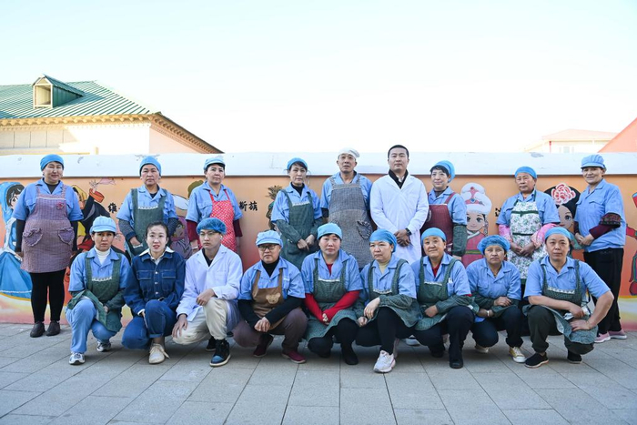 4月1日，在塔城市疆趣食品坊，食品厂创始人王会鹏（后右四）和部分员工在厂区内合影。新华社记者 李响 摄