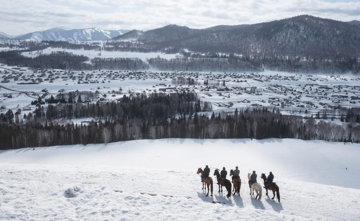　3月30日，苏卡（中）和马队队员在禾木村后山的观景平台上眺望村落。新华社记者 李响 摄