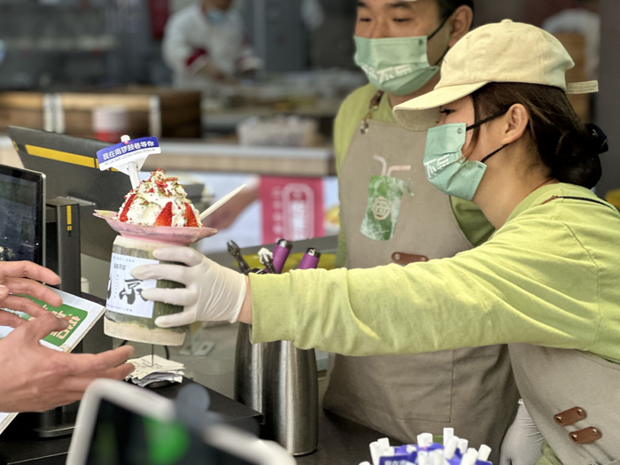 游客在北京南锣鼓巷购买竹筒奶茶。  新京报记者 王子扬 摄