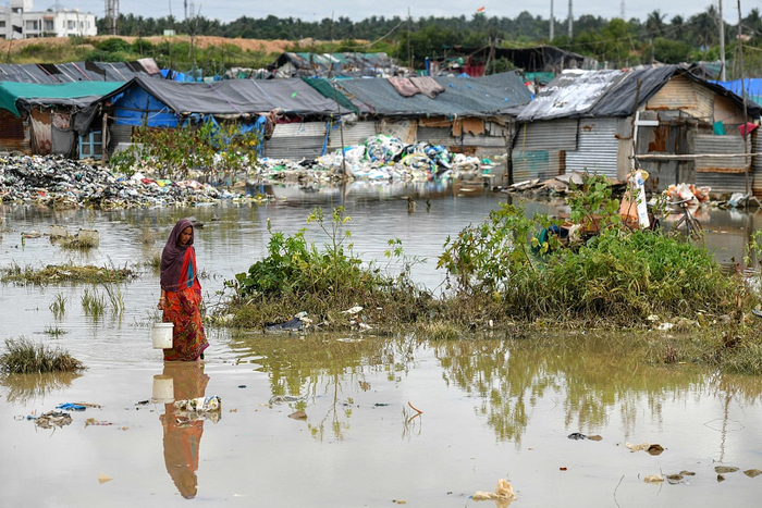 当地时间2022年9月7日，印度班加罗尔，大雨过后，一名居住在贫民窟的妇女艰难地穿过被水浸透的住所。
