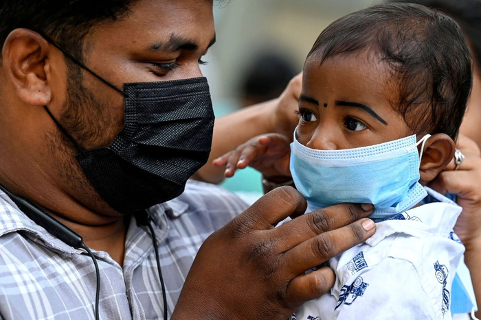 当地时间2023年4月1日，印度金奈新冠病例增加，当地医院内家长为一名儿童戴好口罩。图/视觉中国