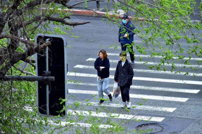 4月20日，辽宁沈阳，春雨来袭，当地急速降温，市民穿着厚衣出行。图/视觉中国