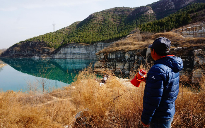 老周拿着他的小喇叭，在湖边提醒游客安全打卡。新京报记者 田杰雄 摄