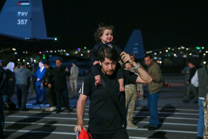 当地时间2023年4月24日，约旦安曼，从苏丹撤离后，一名男子肩上扛着一个哭泣的孩子离开军用机场。视觉中国 图