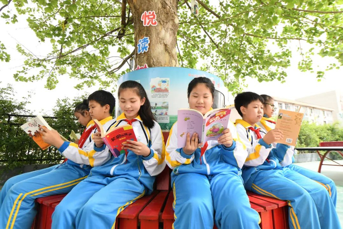 在河北石家庄新乐市东长寿学校，小学生在校园内“悦读树”下读书。贾敏杰 摄
