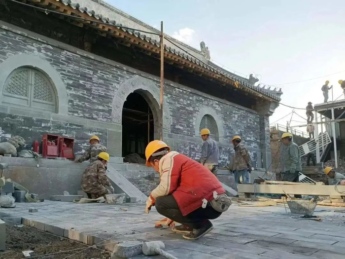 修缮后的山门殿南侧墙体前，施工人员正进行院落路面铺装（图片来源：京诚集团）