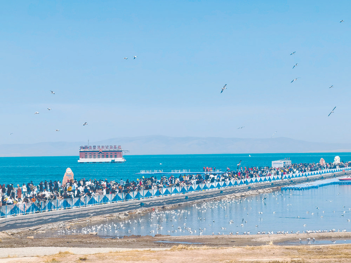 　　游客走近青海湖，感受水天一色美景。图片由青海湖景区提供