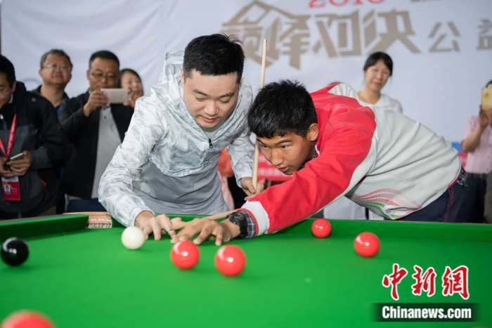 2018“瑞德”斯诺克“巅峰对决”公益活动在西藏启幕，丁俊晖指导藏族学生打台球。何蓬磊 摄