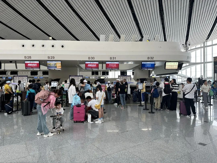 南航值机柜体前旅客有序排队办理值机/记者拍摄