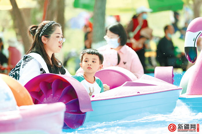 “五一”假期，市民纷纷携家人走进公园，赏花游玩。图为4月30日，市民带着孩子在市植物园划船。