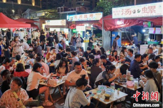5月2日深夜，游客在广西柳州市风情港便民夜市品尝美食。韦国政 摄