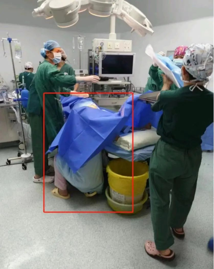 手术台下单膝下跪的助产士