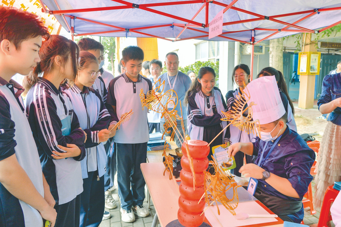 ▲南宁市仙葫学校学生观看职校教师现场制作糖画。    本报记者黄维业 摄