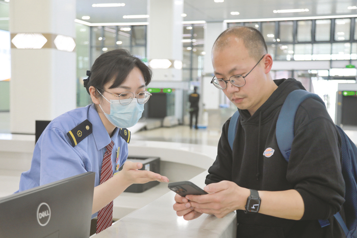     张丽君帮助旅客查询购票信息。    （于莉 摄）