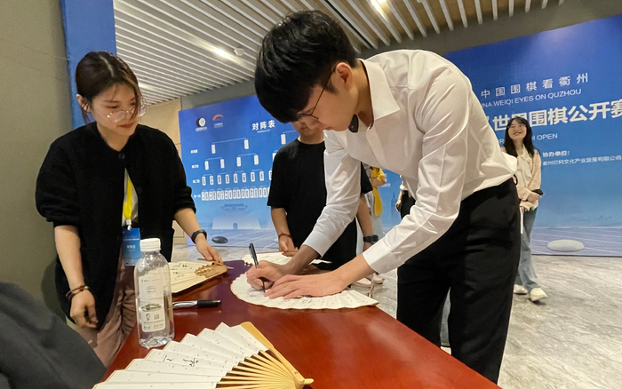 申真谞在扇子上签名。新京报记者 孙海光 摄