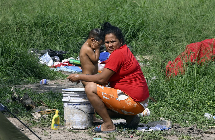 当地时间5月9日，墨西哥马塔莫罗斯，一名妇女在格兰德河岸边的临时营地里给孩子洗澡。