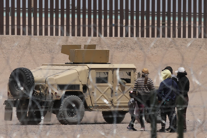 当地时间2023年5月9日，墨西哥华雷斯，移民在格兰德河岸边，等待得州埃尔帕索边境巡逻队进行处理。