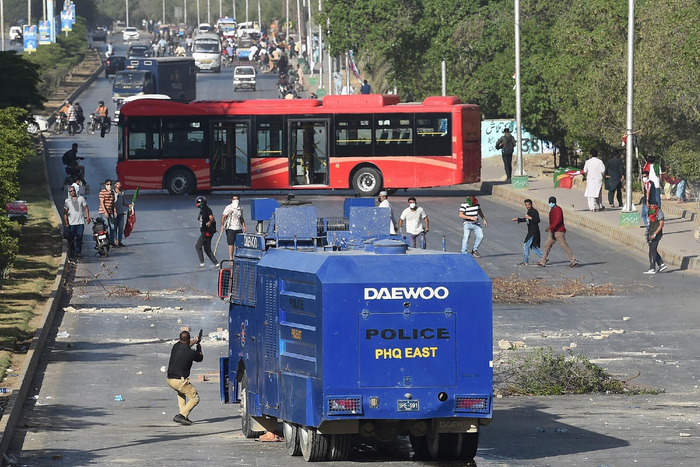 　　当地时间2023年5月9日，巴基斯坦卡拉奇，巴基斯坦前总理伊姆兰·汗的支持者举行抗议活动。一名警察（左）向他们发射催泪瓦斯。图/视觉中国