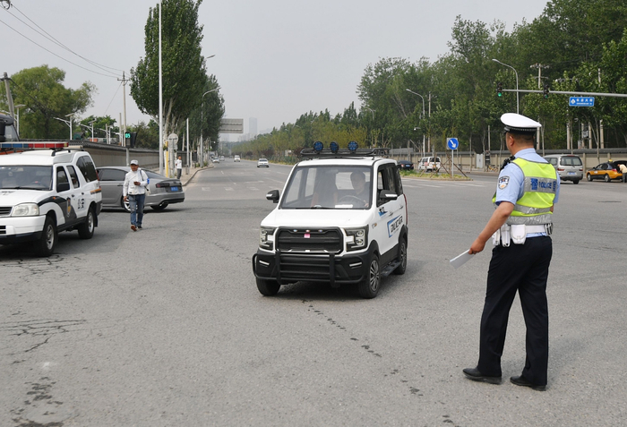 一辆违规电动四轮车被拦下，交警对驾车人进行安全提示。新京报记者 王贵彬 摄