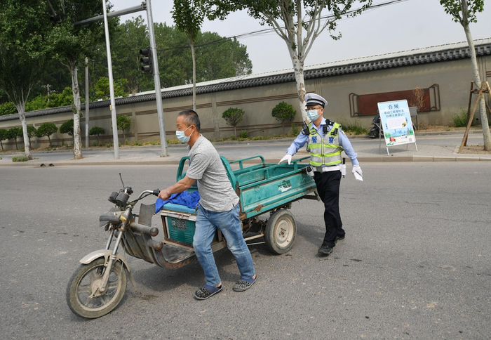 交警引导一辆货运电动三轮车安全通过马路。新京报记者 王贵彬 摄